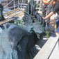 Workers stand on scaffolding to clean bronze statues.